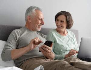 Casal de idosos sentados no sofá e pesquisando sobre a aposentadoria por tempo de contribuição.