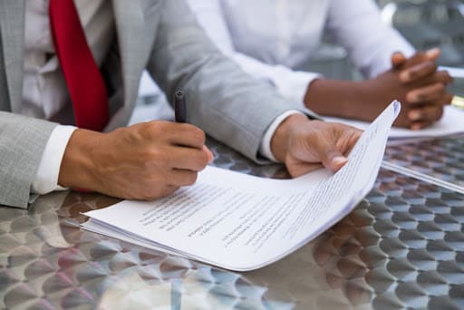 Dois profissionais com as mãos na mesa e papéis, simbolizando o contrato de empréstimo.