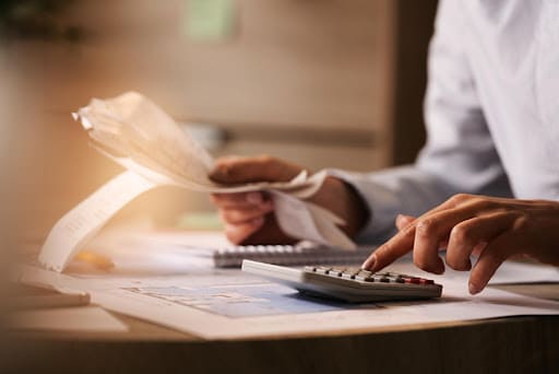 Pessoa sentada na mesa de escritório, com calculadora e papéis, simbolizando o empréstimo consignado.