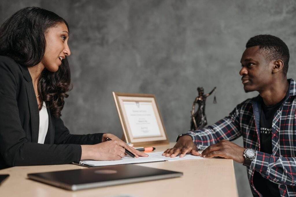 Imagem de homem e mulher conversando sentados em uma mesa, com documentos nas mãos, representando um planejamento previdenciário.