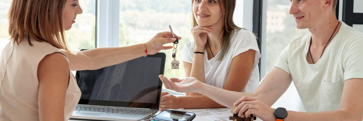 Imagem de mulher entregando as chaves de imóvel para um casal, simbolizando o contrato de compra e venda de imóveis
