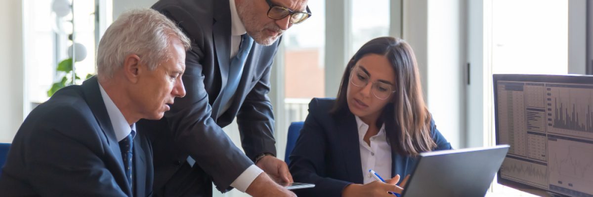 Imagem com três profissionais e um notebook sobre a mesa, simbolizando a discussão de ideias e governança corporativa.