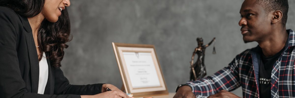 Imagem de homem e mulher conversando sentados em uma mesa, com documentos nas mãos, representando um planejamento previdenciário.